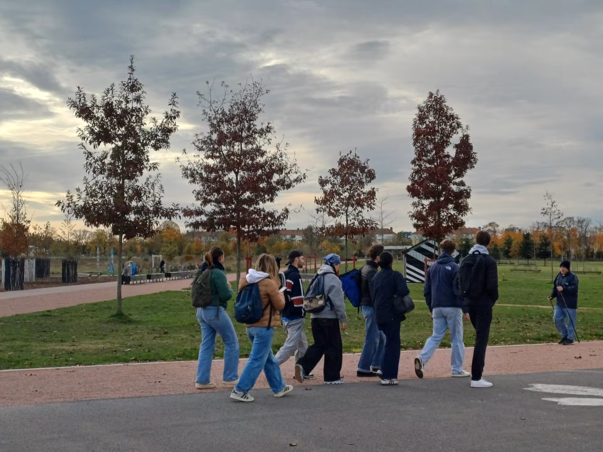 Groupe de personnes marchant sur une allée dans un parc avec des arbres.